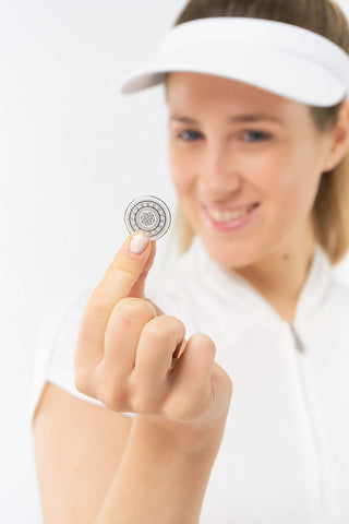 White Clip ladies golf visor constructed with quick-drying fabrics. The visor comes in a one size fits all design which clips around your head to hold it securely in place. It also features a concealed magnet  in peak with a hand enamelled lace effect golf ball marker attached, making it a lovely golf accessory, golf gift! The headband features a soft lined absorbent towel. 